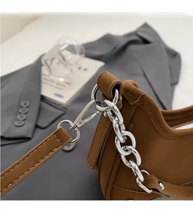 Close-up of premium silver metal chain and D-ring buckle on brown leather shoulder bag