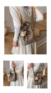 Détail du sac seau en cuir grainé avec un petit ours en peluche et bandoulière