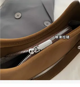 Macro detail of the smooth silver zipper and herringbone fabric lining on a brown leather bag