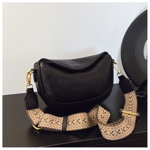 Détail du sac demi-lune noir avec large bandoulière tissée aux motifs géométriques