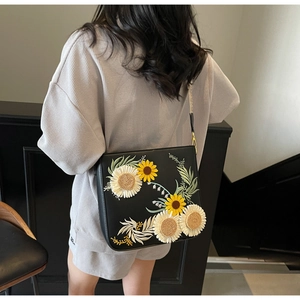 Detail of black leather crossbody bag with 3D sunflower embroidery and adjustable strap