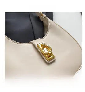 Detailed close-up of a beige leather hobo bag with an elegant golden metal buckle clasp