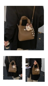 Détail du sac seau marron avec motif litchi, pendentif ours et décor de perles