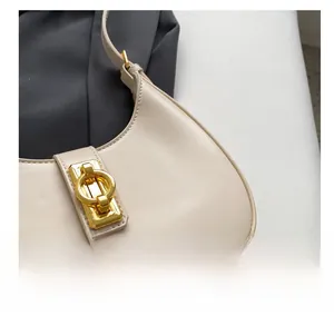 Close-up of cream leather underarm bag featuring a metallic gold twist lock closure