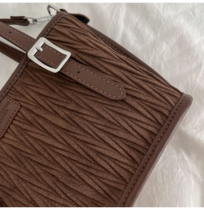 Détail du sac seau marron plissé montrant la bandoulière réglable et la boucle argentée