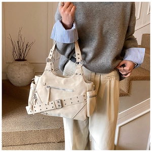 Detail of cream motorcycle bucket bag with silver studs and multi-zipper design