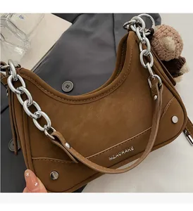 Detail of brown nubuck crescent bag with silver chain and cute knit bear charm