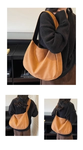 Detail of a large brown suede tote bag with wide shoulder strap worn by a model