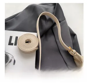 Close-up of a cream PU leather underarm bag strap with vintage gold metal buckle
