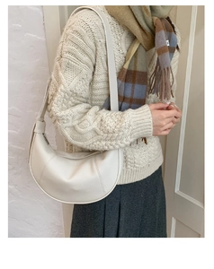 Close-up of creamy white crescent shoulder bag in lychee leather on model sweater