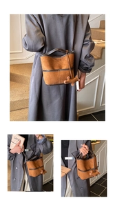 Détail d'un sac seau en daim marron avec surpiqûres contrastées et pendentif chiot