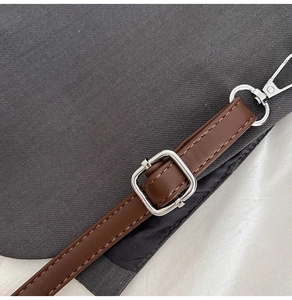 Vue détaillée du sac seau en toile gris foncé avec bandoulière réglable en cuir brun