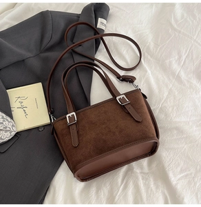 Vue détaillée du sac seau marron avec texture en daim et boucle sur literie blanche