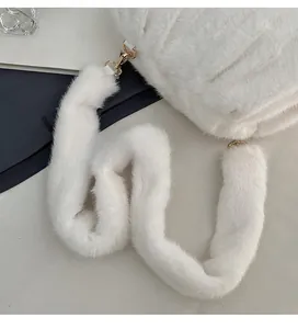 Detail of white faux fur crossbody bag featuring plush shoulder strap and gold metal hooks