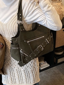 Dark green rivet bucket bag with silver studs and zippers shown on a model