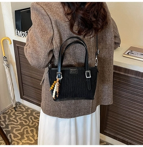 Détail du sac seau noir texturé avec perles en bois rétro et boucle argentée vintage