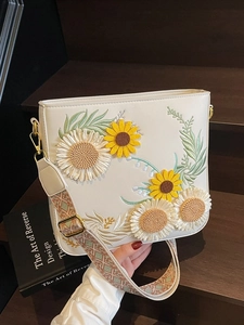 White bucket bag with sunflower embroidery and a bohemian style wide woven shoulder strap