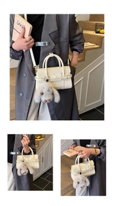 Detail of white PU leather crossbody bag with cute plush rabbit charm and top handles