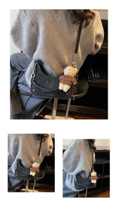 Black matte crescent bag with gold chain strap and teddy bear charm on book shelf