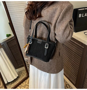 Détail du sac cabas plissé noir en similicuir avec poignées rondes et breloque perlée