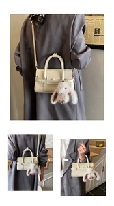 Detail of minimalist cream crossbody bag with leather buckle and plush bunny charm