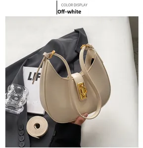 Detail of beige crescent underarm bag with gold circular lock and extra strap