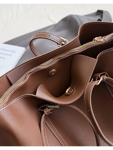 Detail of vintage brown tote featuring white contrast stitching and gold metal zipper
