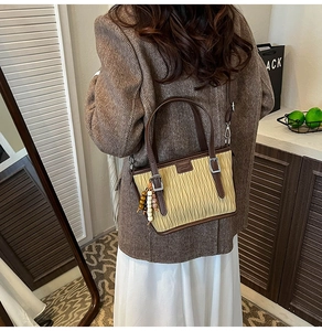 Détail du sac seau rétro plissé avec garniture en cuir brun et pendentif ethnique