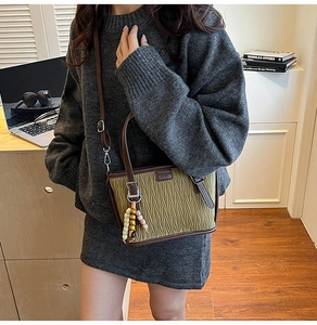 Détail du sac seau plissé vert foncé avec bandoulière en cuir et pendentif perlé