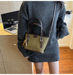 Détail du sac seau plissé vert avec poignées en cuir marron et pendentif à perles
