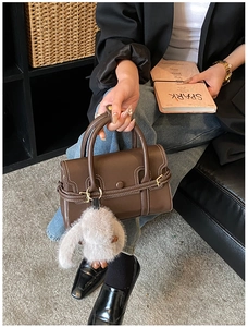Detail of dark brown leather bowling bag with contrast stitching and rabbit charm