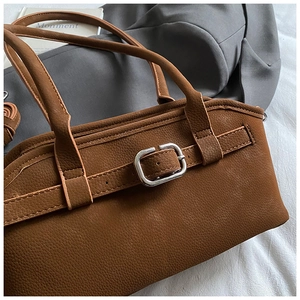 Détail macro du sac à main en cuir grainé caramel avec boucle métallique argentée