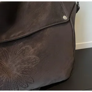 Close-up of soft brown leather tote bag with vintage embossed daisy flower patterns