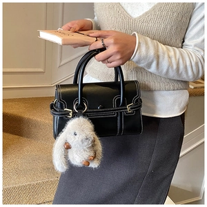 Detail of minimalist black leather bowling bag with contrast stitching and rabbit charm