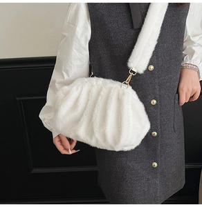 Detail of white faux fur cloud bag with soft pleated texture and gold metal hooks