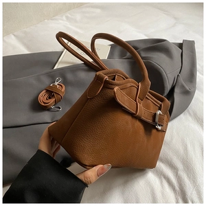Gros plan détaillé d'un sac à main marron à grain litchi avec sa bandoulière assortie