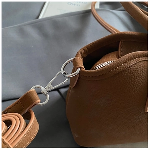 Détail du sac à main en cuir grainé avec crochet en métal argenté et bandoulière amovible