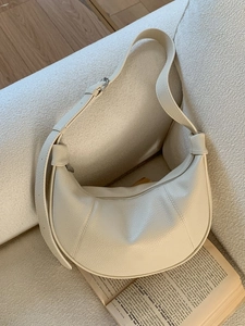 Chic off-white leather hobo bag with knotted strap on sofa for winter fashion
