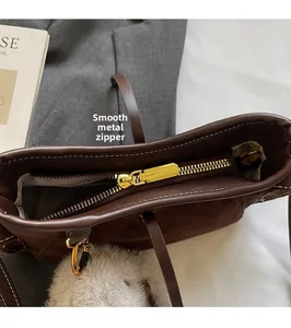 Detail view of smooth golden hardware zipper on a dark brown suede baguette bag