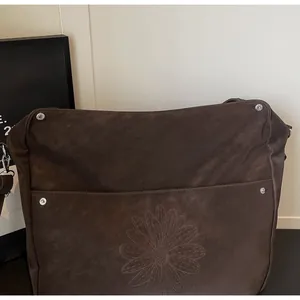 Detail of dark brown leather texture with embossed daisy pattern and metal rivets
