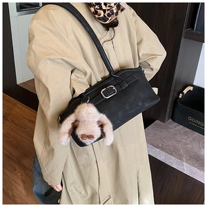 Détail d'un sac à main noir vintage avec breloque en peluche et boucle métallique