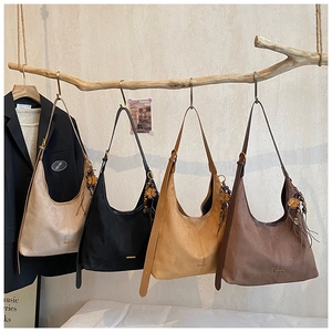 Détail de quatre sacs cabas en daim coloré suspendus avec des breloques florales