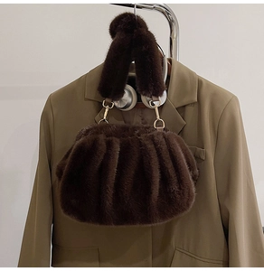 Detail of plush brown faux fur cloud bag with gold metal buckle and pleated handle