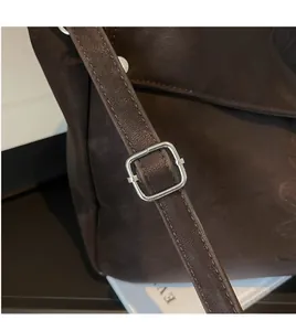 Detail of dark brown matte leather tote bag with adjustable silver metal buckle strap