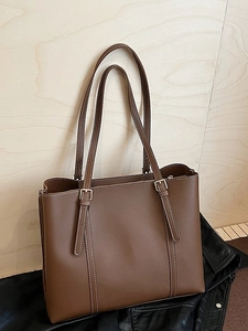 Brown leather tote bag with white contrast stitching and adjustable silver buckle strap
