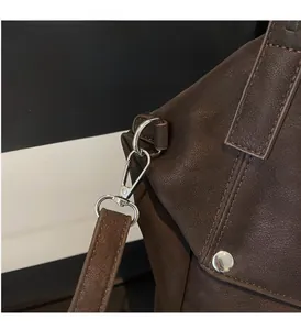 Close-up of deep brown textured leather tote with silver metal hooks and premium stitching