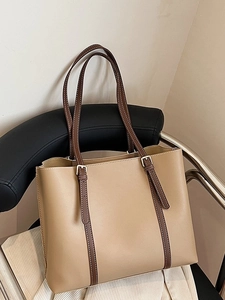 Large vintage leather tote bag in beige and brown with adjustable strap on a chair