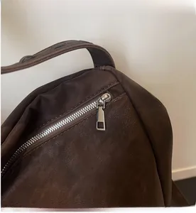Detail shot of smooth silver zipper and dark brown lychee texture leather shoulder bag