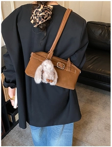 Gros plan du sac bandoulière marron avec boucle en métal et breloque lapin en peluche
