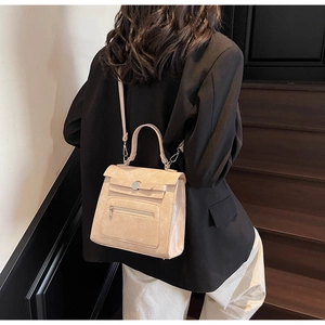 Detail of the beige trapezoid leather handbag featuring a top handle and functional zipper